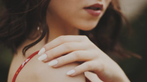 close up of woman in red spaghetti strap top | Lizzo's Trendy Milky White Nails We Absolutely Love | Featured