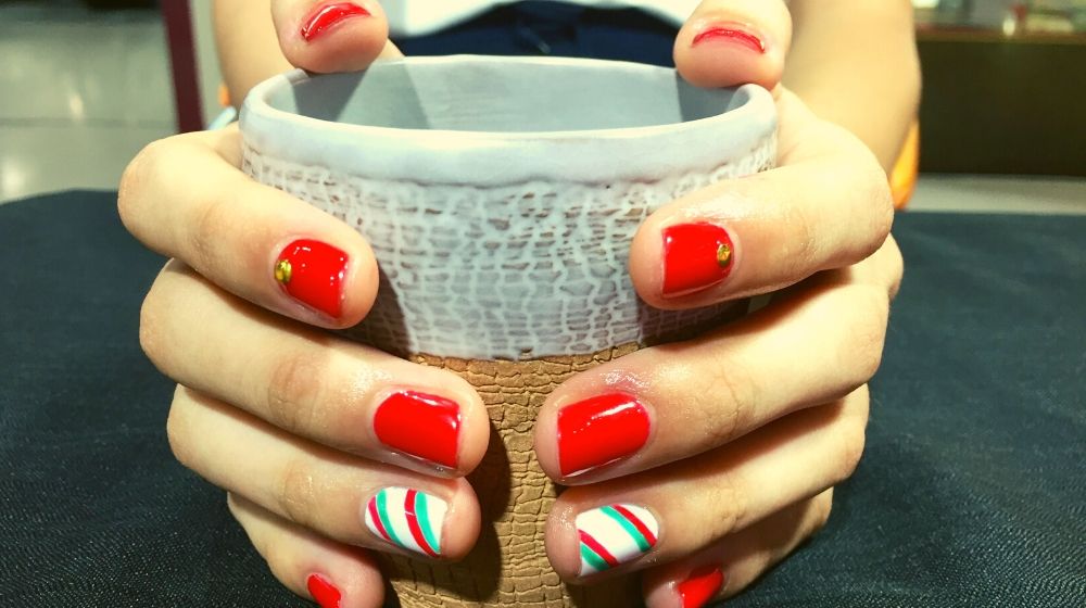 Candy cane nails while holding a cup | Sexy Red Nail Designs You Should Wear This Christmas