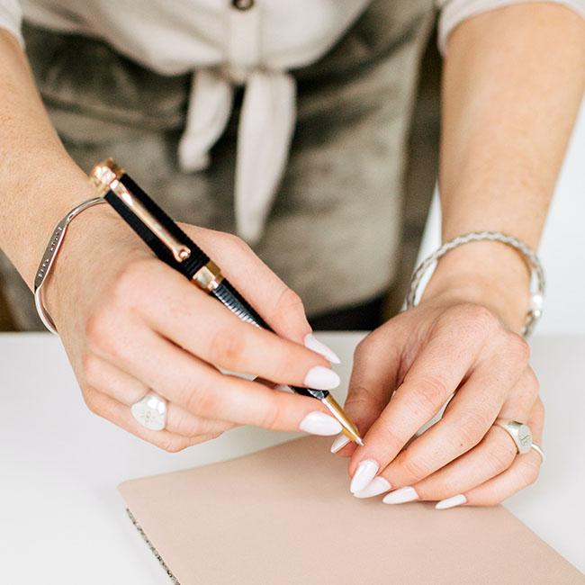 person holding pen near journal book | Lizzo's Trendy Milky White Nails We Absolutely Love